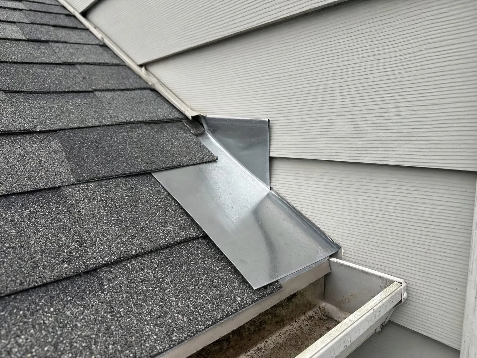 Metal kick-out flashing at the bottom of a roof-to-wall joint, turning water into the gutter